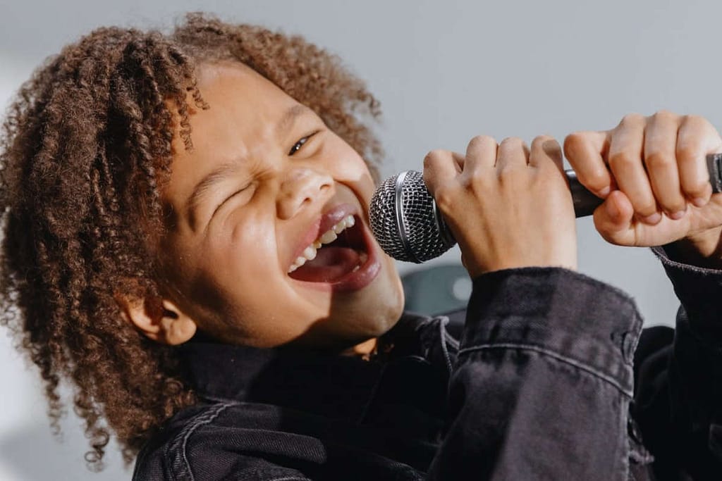 A little boy displaying the godly character "joy" by singing into a microphone.