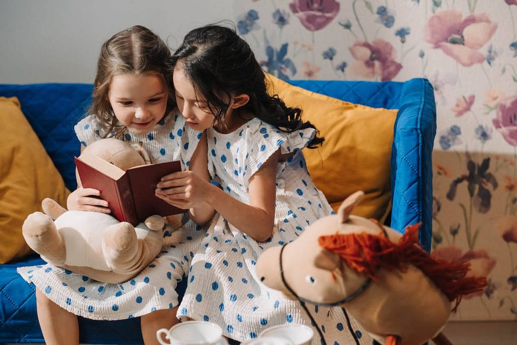 Two girls sitting on a couch reading about the fruit of the Spirit Love.